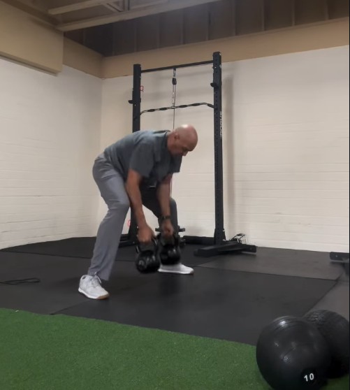 The Peak Strength and Fitness gym floor with squat racks, dumbbells and members training