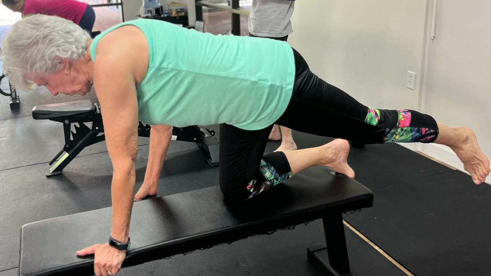 An older member working through a core exercise with coaching